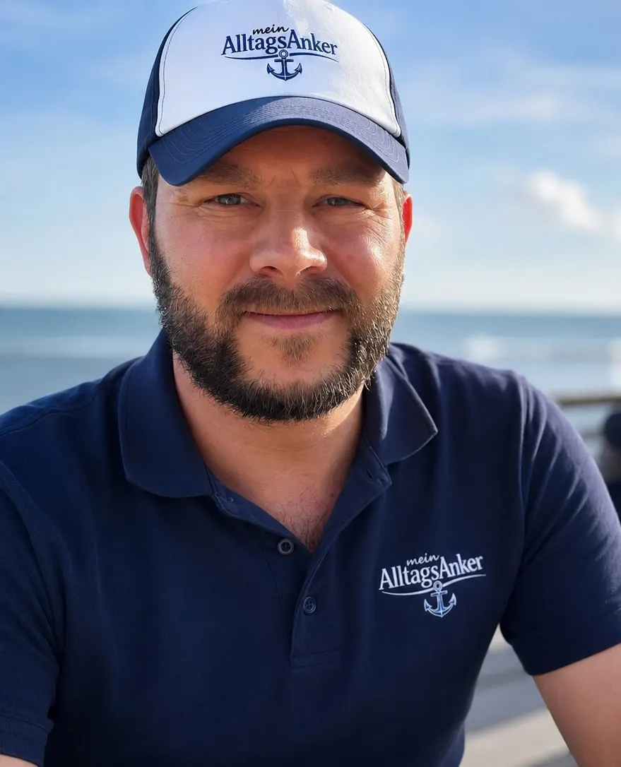 Maximilian Schulze, Inhaber von mein AlltagsAnker, in Poloshirt und Cap mit Firmenlogo an der Ostsee